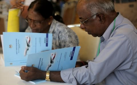 Family members read MH370 briefing reports before a closed door meeting - Credit: Reuters