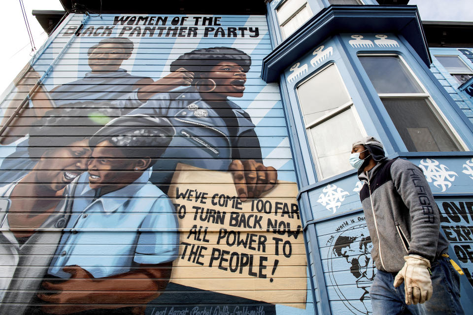 A man passes a mural celebrating the Black Panther Party in Oakland, Calif., on Wednesday, Oct. 13, 2021. The home sits across the street from where Black Panther Party co-founder Huey Newton was shot and killed in 1989. A lesser-known fact was that a majority of the party's membership, as well as its leadership outside of the central organizing committee in Oakland, were Black women. (AP Photo/Noah Berger)