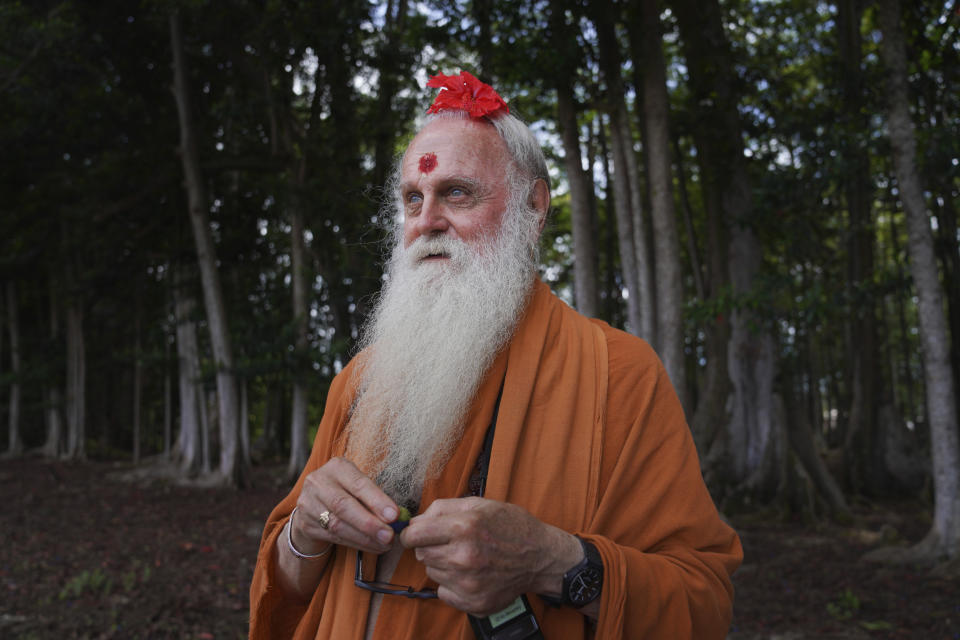 Paramacharya Sadasivanatha Palaniswami stands at the edge of the Rudraksha forest peeling one of its sacred fruits, at the Kauai Hindu Monastery on July 9, 2023, in Kapaa, Hawaii. (AP Photo/Jessie Wardarski)