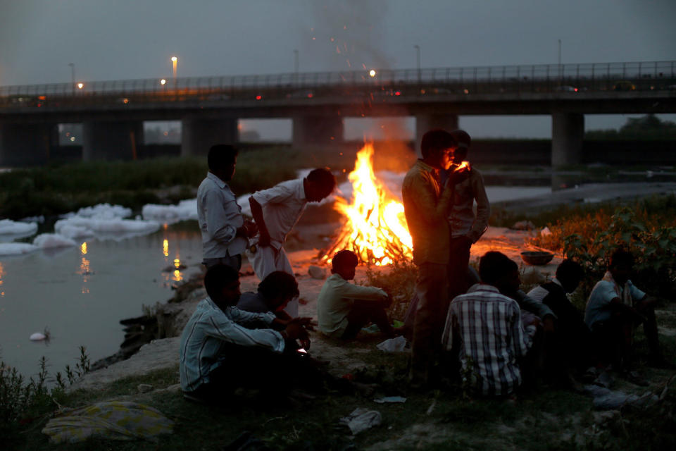 Men watch the fires of a cremation along the banks of the Yamuna River against the backdrop of the Wazirabad Barrage and floating industrial waste. <i>From the story "<a href="http://www.npr.org/2016/05/11/477415686/can-indias-sacred-but-dead-yamuna-river-be-saved" target="_blank">Can India's Sacred But 'Dead' Yamuna River Be Saved</a>?" 2016.&nbsp;</i>