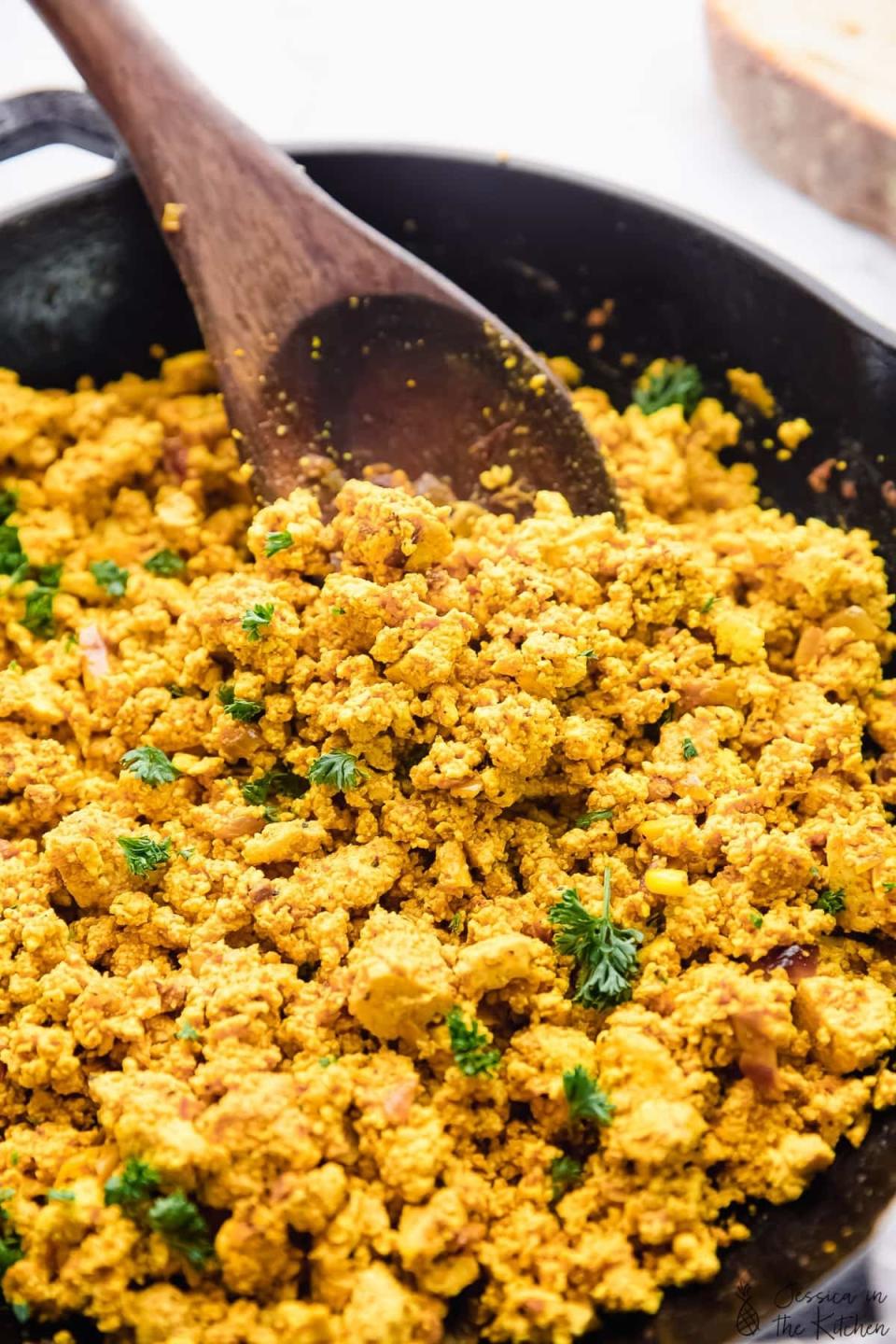 A large skillet filled with a tofu scramble that resembles scrambled eggs in texture.