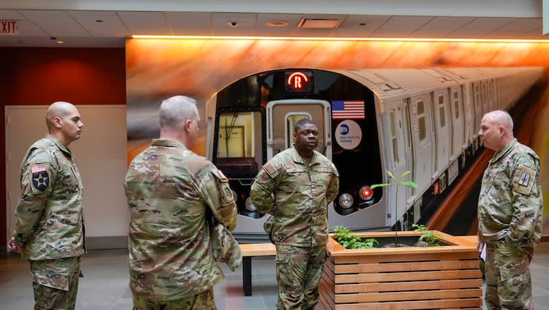 Members of the Armed Forces, including the National Guard, wait in the lobby of the New York City Mass Transit Authority Rail Control Center before the start of a news conference with Gov. Kathy Hochul, Wednesday, March 6, 2024, in New York. Hochul is deploying the National Guard to the New York City subway system to help police search passengers' bags for weapons, following a series of high-profile crimes on city trains.