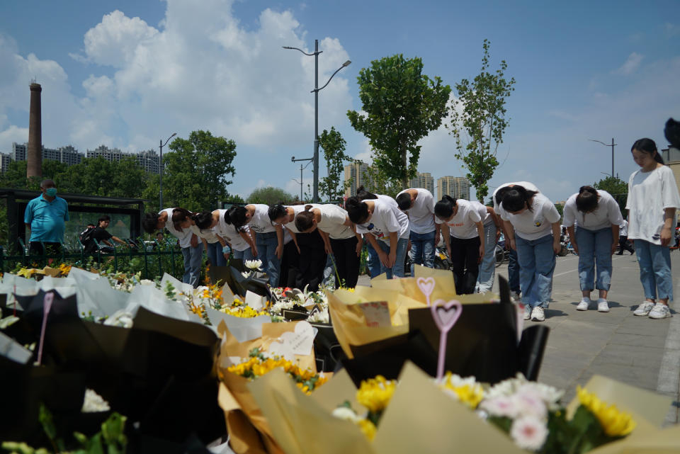 People bow to pay their respects outside the entrance to a subway station in Zhengzhou in central China's Henan Province, Tuesday, July 27, 2021. Residents laid flowers on Tuesday at the entrance of the subway station where more than a dozen people died after a record-breaking downpour flooded large swaths of Henan province in central China. (AP Photo/Dake Kang)