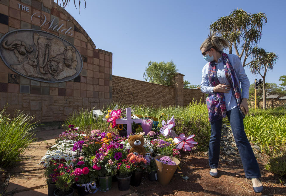 Christine Wright leaves flowers outside the complex where the Dickason family lived prior to their emigration to New Zealand, in Pretoria, South Africa, Thursday, Sept. 23, 2021. People in the town of Timaru are planning an evening vigil outside the home of three young girls who were killed last week in a crime that shocked New Zealand. The girls' mother Lauren Dickason has been charged with their murder. (AP Photo/Themba Hadebe)