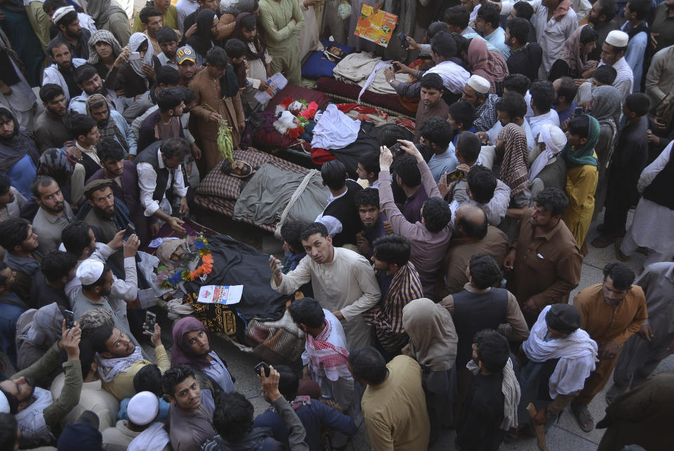 Afghan people stand over bodies of civilians during a protest in Nangarhar province east of Kabul, Afghanistan, Saturday, May 25, 2019. Afghan officials say at least six civilians, including a woman and two children, have been mistakenly killed in an Afghan security forces raid against Taliban fighters in eastern Nangarhar province. (AP Photo/Mohammad Anwar Danishyar)