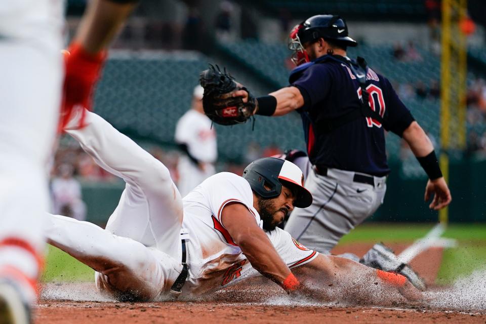 Baltimore Orioles' Anthony Santander, bottom, slides in ahead of the tag by Cleveland Guardians catcher Mike Zunino on a sacrifice fly ball by Orioles' Austin Hays during the second inning of a baseball game, Tuesday, May 30, 2023, in Baltimore. (AP Photo/Julio Cortez)