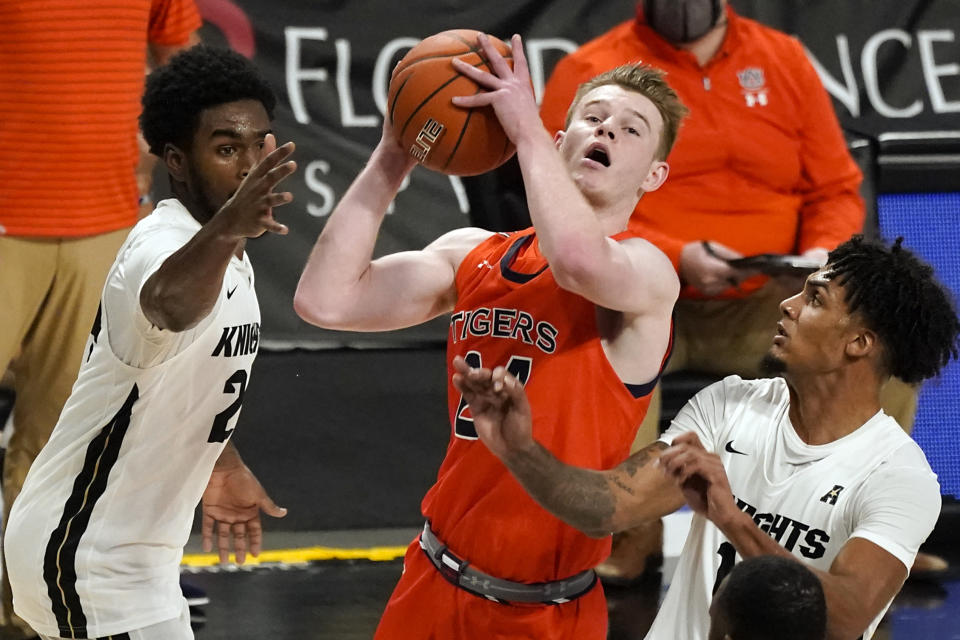 Auburn guard Justin Powell, center, shoots as he gets between Central Florida guard Dre Fuller Jr., left, and guard Brandon Mahan, right, during the second half of an NCAA college basketball game, Monday, Nov. 30, 2020, in Orlando, Fla. (AP Photo/John Raoux)