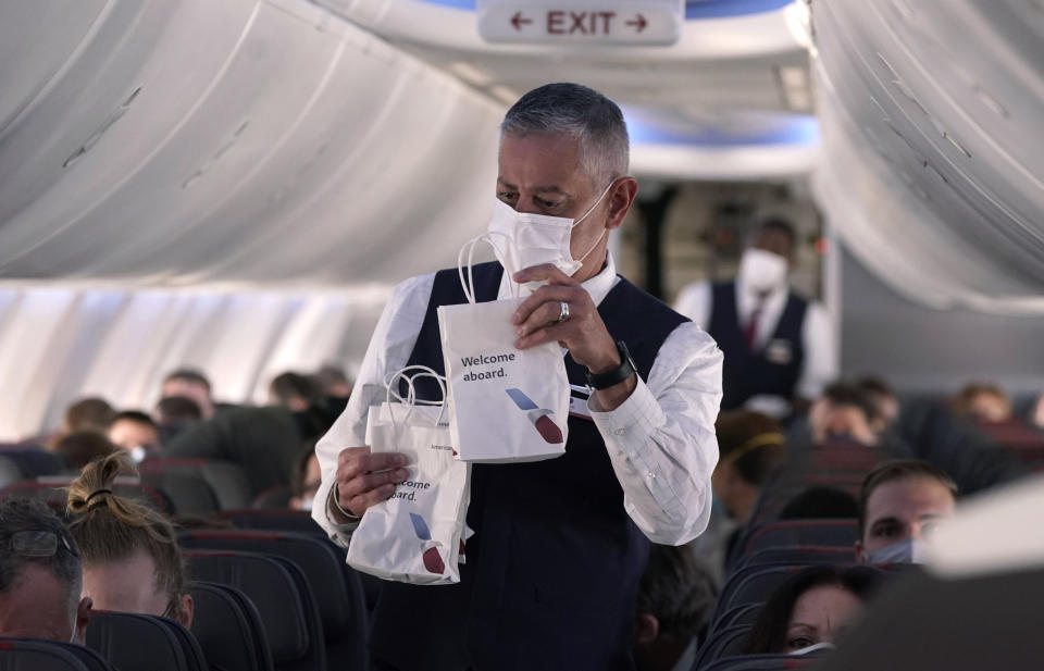 FILE - In this Dec. 2, 2020, file photo, an American Airlines flight attendant hands out snack bags aboard a Boeing 737 Max jet before taking off from Dallas Fort Worth airport in Grapevine, Texas. Airlines executives told legislators on Wednesday, Dec. 15, 2021, they are having trouble hiring pilots, flight attendants and other personnel, and that’s part of what is causing canceled flights and scrapping of service to some airports. (AP Photo/LM Otero, File)