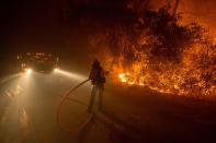 <p>Sampson Spence of Fremont Fire douses flames as they approach a road in the Santa Cruz Mountains near Loma Prieta, California on September 28, 2016. The Loma Fire has charred more than 2000 acres and burned multiple structures in the area. (Josh Edelson/AFP/Getty Images) </p>