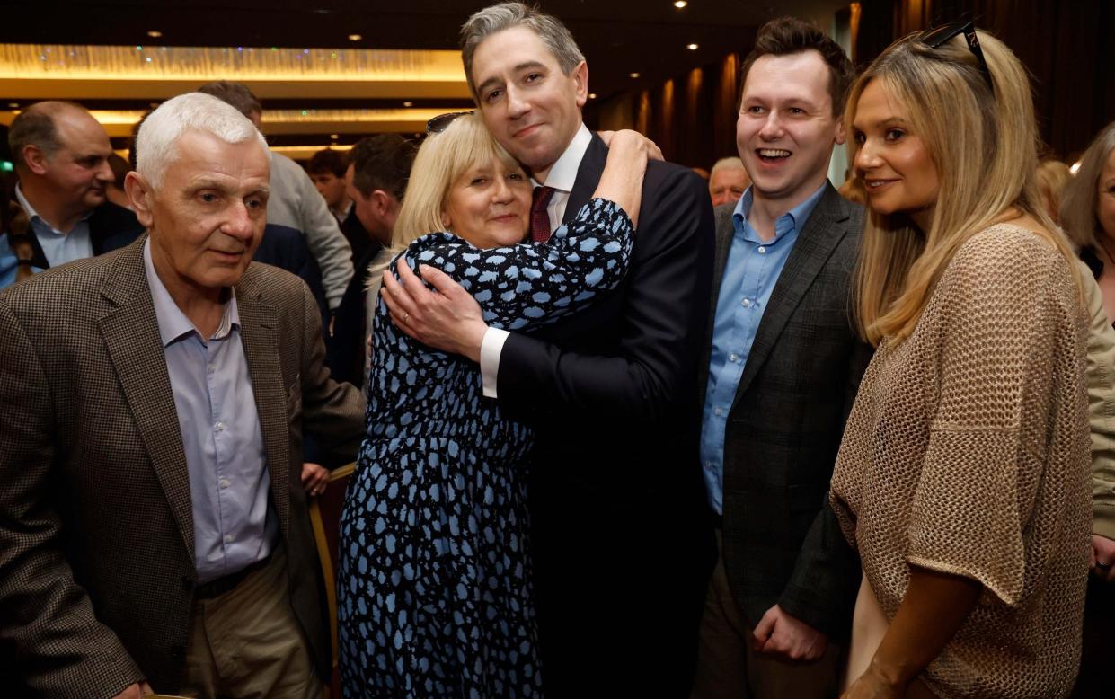 Simon Harris hugs his mother Mary and is congratulated by his father Bart (left) and his brother, Adam (right)