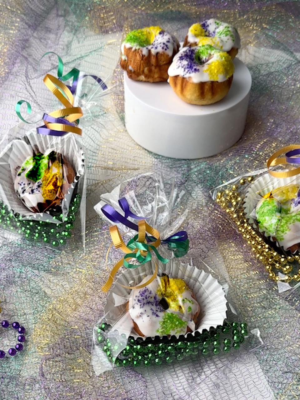 King Cake, a sweet pastry made with a rich buttery dough, is filled with sugar and cinnamon, topped with frosting, and finished with purple, green, and yellow sprinkles.