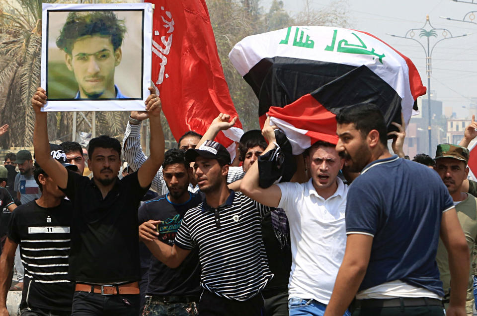 Mourners chant anti government slogans while carrying the Iraqi flag-draped coffin of Mekki Yasser, seen in the poster, a protester whose family and activists said he was killed when he participated in a protest last night, during his funeral on Tuesday, Sept. 4, 2018, in Basra, about 340 miles (550 kilometers) southeast of Baghdad, Iraq. (AP Photo/Nabil al-Jurani)