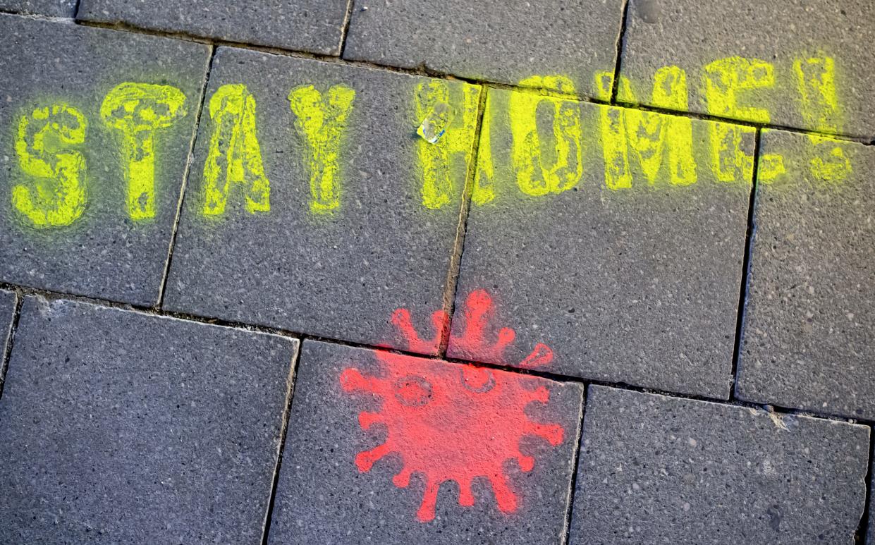 A graffiti consisting of the text "Stay Home" and a symbolic novel coronavirus has been sprayed on the ground in Munich, Germany, Monday March, 16, 2020.