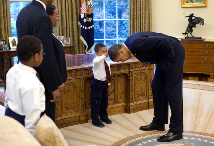 Jacob Philadelphia, a 5-year-old Black boy, touches Barack Obama's hair in the Oval Office as members of the boy's family watch.