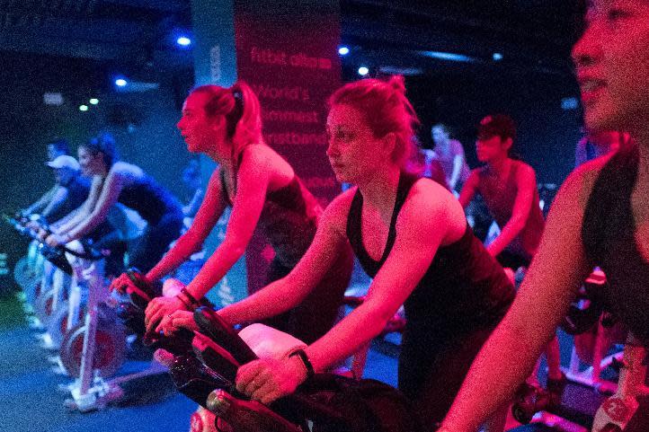 In this March 1, 2017 photo, women wear Fitbit's new Alta HR on their wrist while working out at a Swerve fitness center in New York. Fitbits already track how much people sleep and use sensors to measure periods of being awake or restless while in bed. Now, using a built-in heart-rate monitor, the devices will break sleep into clinically defined stages. (AP Photo/Mark Lennihan)