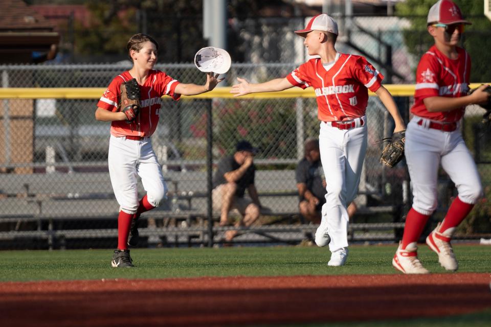 Holbrook vs. East Hanover in the New Jersey Little League Baseball tournament at Buchmuller Park in Secaucus on Saturday, July 29, 2023. Holbrook #10 Mason Monday throws #4 Quinn DautÕs hat back to him after Daut lost his hat while making a catch.