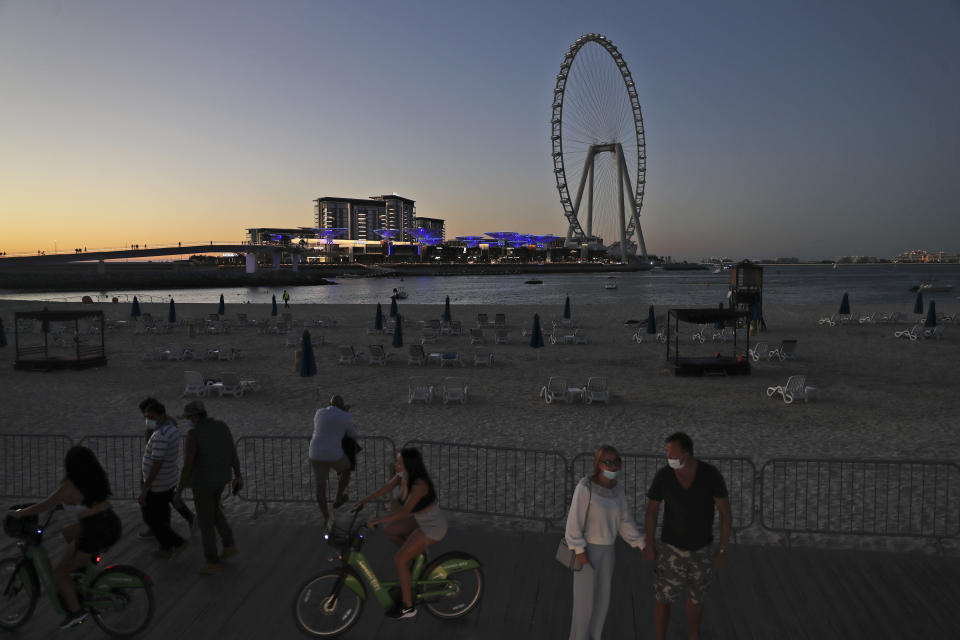 Tourists and residents enjoy the sunset at the Jumeirah Beach Residence, in Dubai, United Arab Emirates, Tuesday, Jan. 12, 2021. Coronavirus infections are surging to unprecedented heights in the United Arab Emirates. But Dubai, the glimmering city-state powered by legions of foreign laborers and travelers, is resisting a lockdown during its peak tourism season. (AP Photo/Kamran Jebreili)