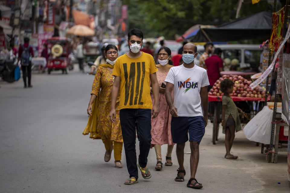 People wearing masks as a precaution against the coronavirus walk through a market in New Delhi, India, Thursday, Aug. 11, 2022. The Indian capital reintroduced public mask mandates on Thursday as COVID-19 cases continue to rise across the country. (AP Photo/Altaf Qadri)