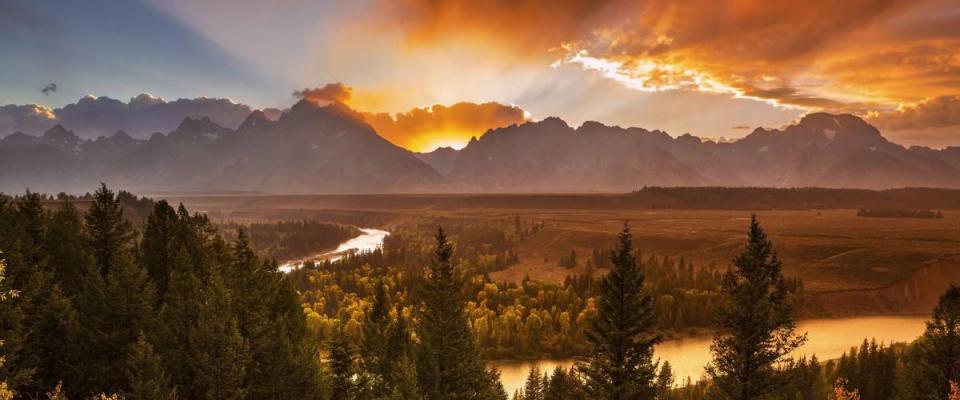 The sun sets behind the Teton Range and Snake River in Grand Teton National Park, Wyoming.