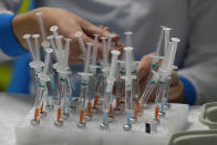 FILE - A nurse prepares vaccines in the Wizink Center, currently used for COVID-19 vaccinations in Madrid, Dec. 1, 2021. With one of Europe's highest vaccination rates and its most pandemic-battered economies, the Spanish government is laying the groundwork to approach the virus in much the same way countries deal with flu or measles. (AP Photo/Paul White, File)