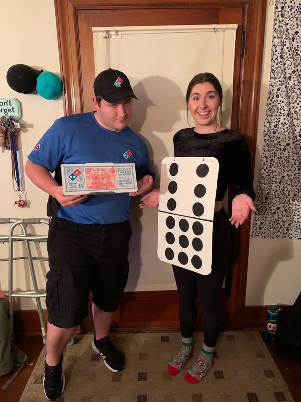 A man in a Dominos uniform and a woman dressed as a domino pose for a photo.