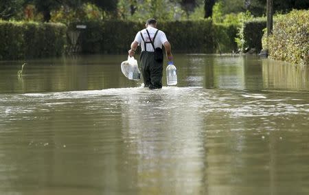 A man carrying food and drinking water wades through a flooded street in Zazina village, central Croatia, September 15, 2014. REUTERS/Antonio Bronic