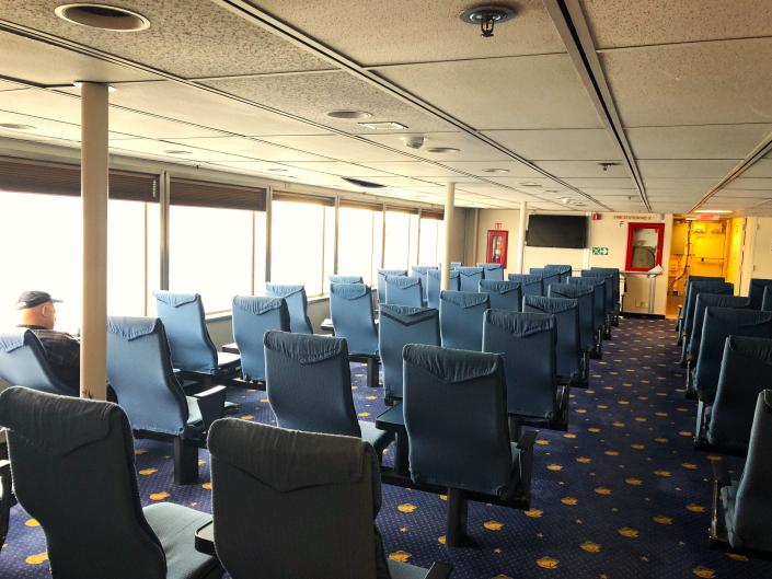 A seating area on a ferry with mostly empty seats.