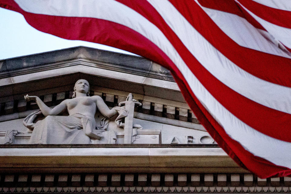 FILE - An American flag flies outside the Department of Justice in Washington, March 22, 2019. The Justice Department has announced its largest-ever financial seizure — more than $3.5 billion — and the arrests of a New York couple accused of conspiring to launder billions of dollars in cryptocurrency. It says the cryptocurrency was stolen from the 2016 hack of a virtual currency exchange. Law enforcement officials on Tuesday revealed the Justice Department has seized roughly $3.6 billion in cryptocurrency linked to the hack of Bitfinex, a virtual currency exchange whose systems were breached nearly six years ago. (AP Photo/Andrew Harnik, File)