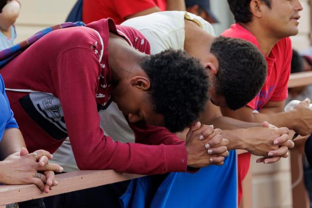 Two migrants bow their heads during a prayer at a vigil at the Ozanam Center, a homeless and migrant shelter, on 8 May 2023 in Brownsville, Texas (Getty Images)