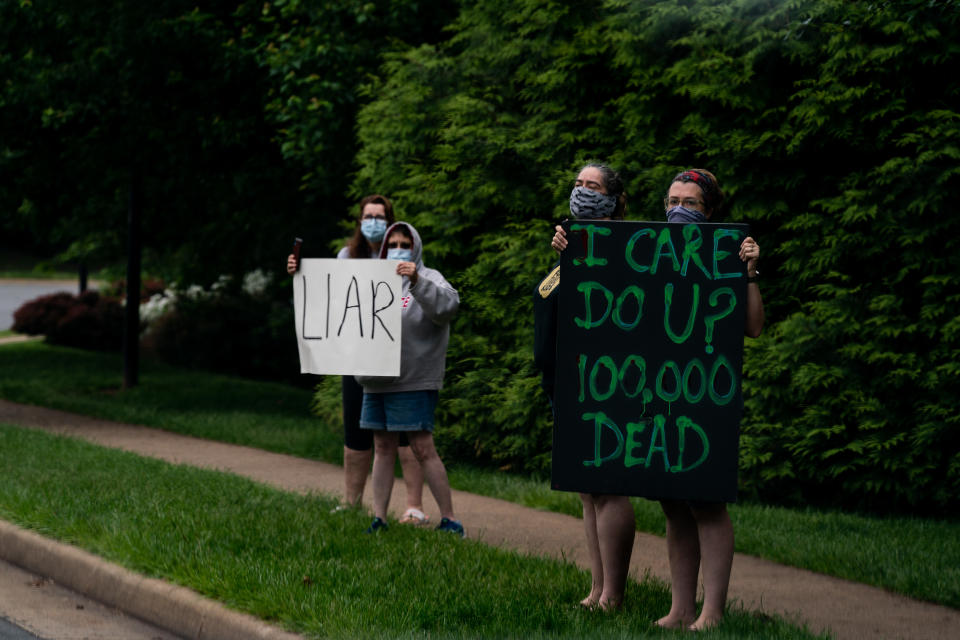 Varios manifestantes levantan pancartas durante el recorrido del convoy del presidente Donald Trump hacia el Trump National Golf Club en Sterling, Virginia, el 24 de mayo de 2020. (Anna Moneymaker/The New York Times)