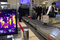 Passengers wearing face masks to protect against the spread of new coronavirus pass through security checks near a temperature scanner at Hankou train station after of the resumption of train services in Wuhan in central China's Hubei Province, Wednesday, April 8, 2020. After 11 weeks of lockdown, the first train departed Wednesday morning from a re-opened Wuhan, the origin point for the coronavirus pandemic, as residents once again were allowed to travel in and out of the sprawling central Chinese city. (AP Photo/Ng Han Guan)