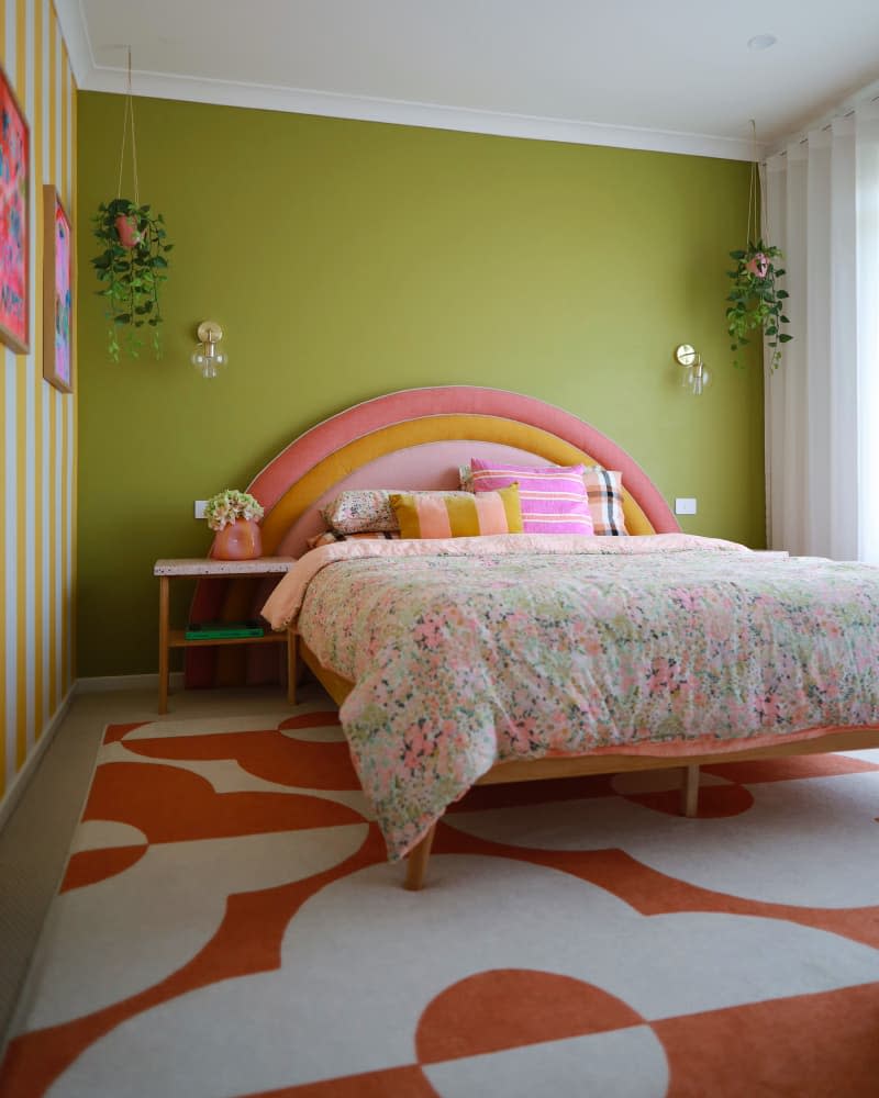 Green painted walls in colorful bedroom with rainbow headboard.