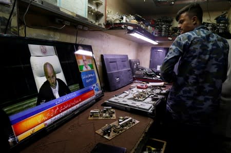 A technician looks at television screen displaying the coverage of the World Court review of the death penalty given to former Indian navy commander Kulbhushan Sudhir Jadhav, at his shop in Karachi