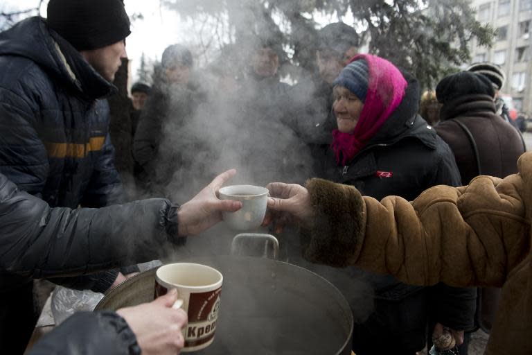 Elderly residents queue up for hot tea and biscuits at a makeshift soup kitchen on Lenin square in Debaltseve on March 2, 2015