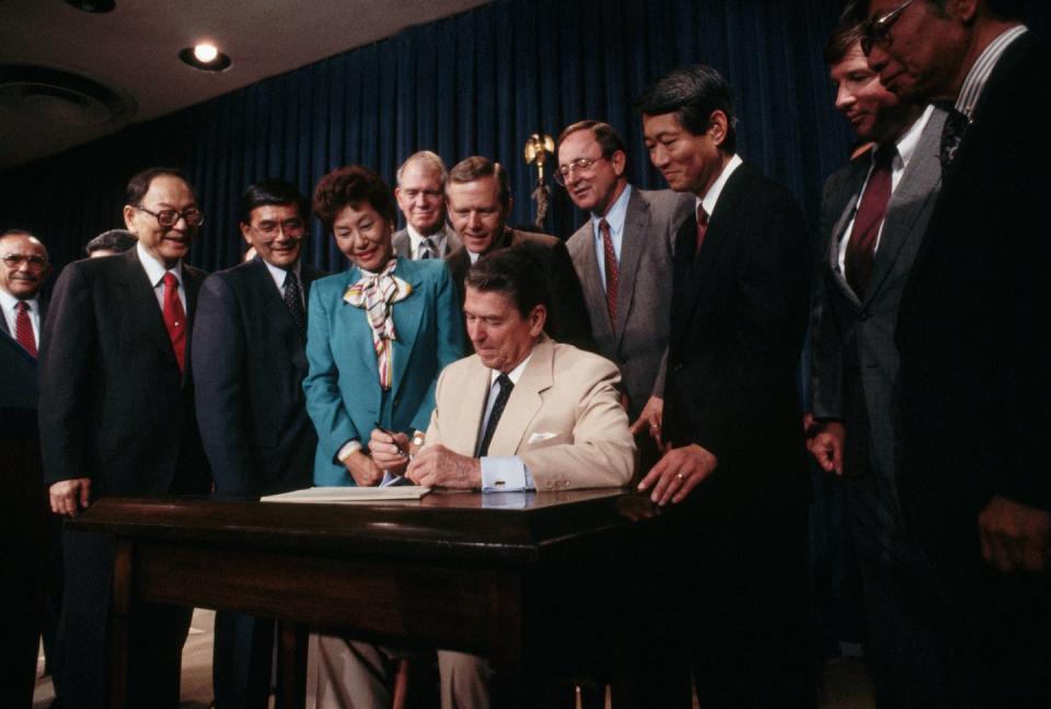 Congressmen surround President Ronald Reagan.