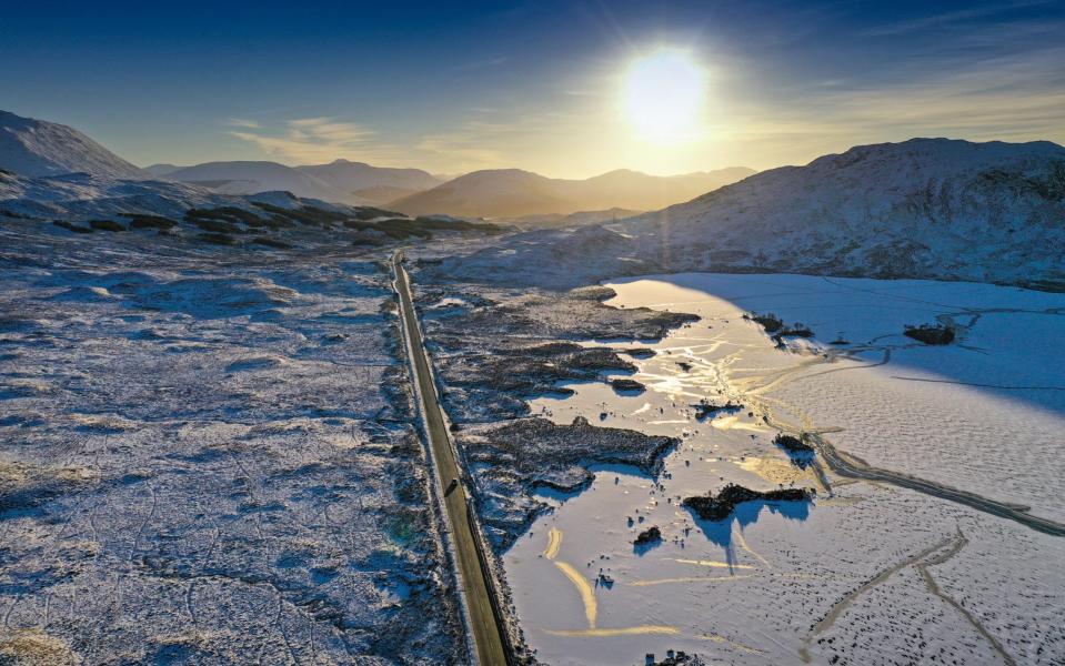 A vehicle travels on the A82 past a frozen over Lochan na Achlaise as freezing temperatures continue in Glen Coe - Getty