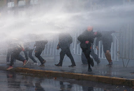 Demonstrators are hit by a jet of water from a riot police vehicle during a protest demanding an end to profiteering in the education system in Santiago, Chile April 19, 2018. REUTERS/Rodrigo Garrido