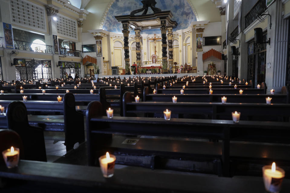 Lighted candles are placed on empty pews as Catholic priest presides over a Palm Sunday mass to prevent the spread of the coronavirus at the Saint Peter Parish Church in Quezon city, Philippines on March 28, 2021. The government banned religious activities during the Holy Week as it enters into stricter lockdown measures starting next week while the country struggles to control an alarming surge in COVID-19 cases. (AP Photo/Aaron Favila)