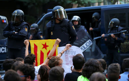 A protestor holds up an Estelada (Catalan independence flag) in front of a line of Spanish national police who surrounded the leftist Popular Unity Candidacy (CUP) party headquarters in Barcelona, Spain, September 20, 2017. REUTERS/Albert Gea