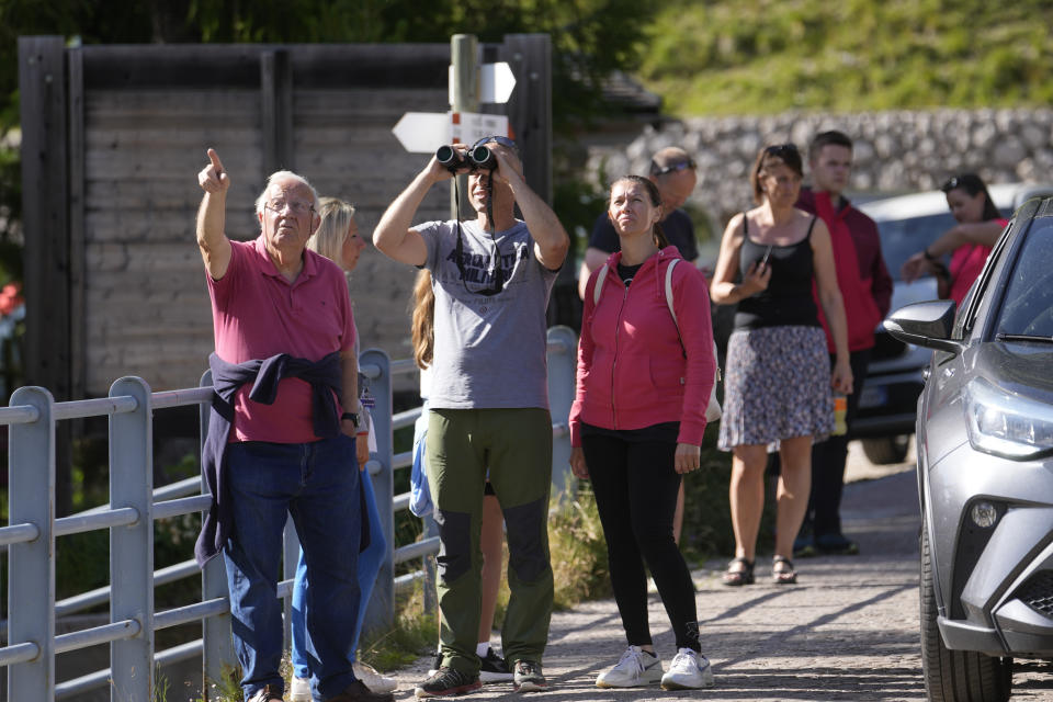 People look at the Punta Rocca glacier near Canazei, in the Italian Alps in northern Italy, Monday, July 4, 2022, a day after a huge chunk of the glacier broke loose, sending an avalanche of ice, snow, and rocks onto hikers. Rescuers said conditions downslope from the glacier, which has been melting for decades, were still too unstable to immediately send rescuers and dogs into the area to look for others buried under tons of debris. (AP Photo/Luca Bruno)