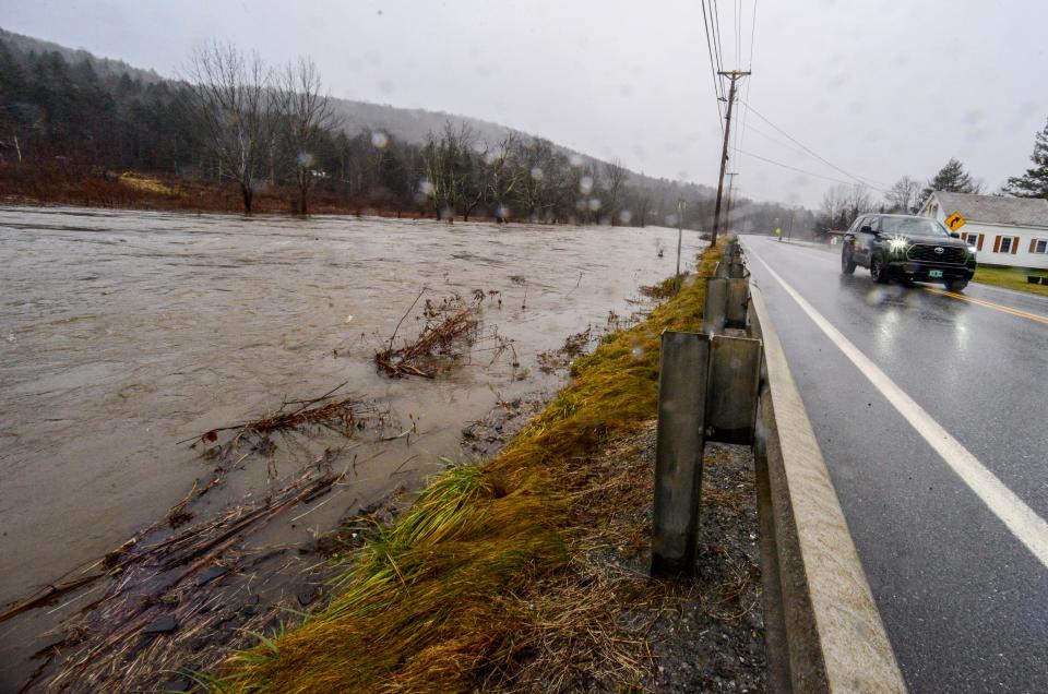 The water level of the Deerfield River creeps up to the edge of Route 100 in Wilmington (AP)