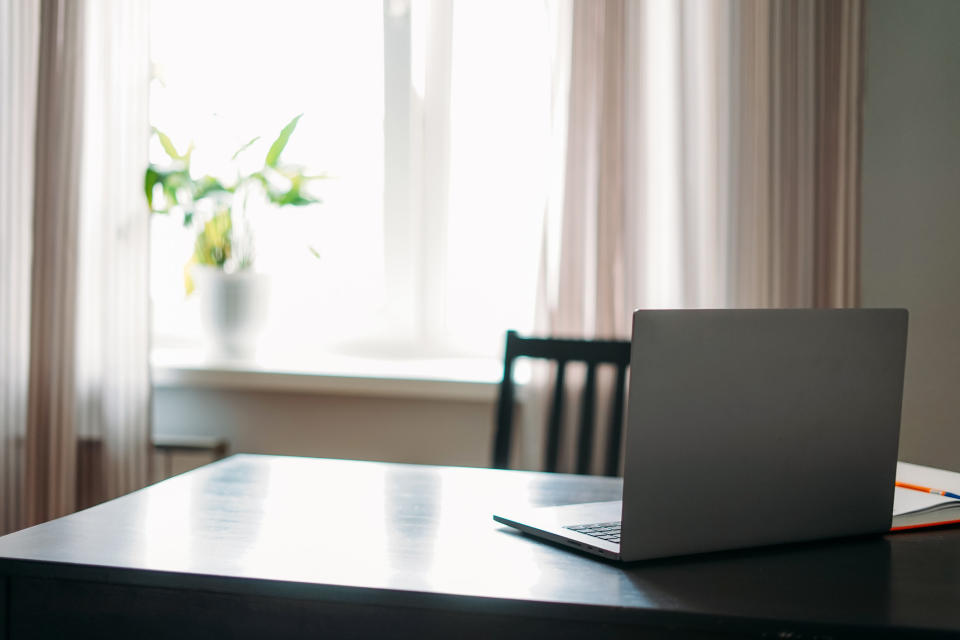 Opened Laptop Notebook On Black Table With Mobile Phone And Notes Against Window At Home