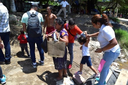 A man helps a Guatemalan migrant and her daughter to leave a raft after crossing the Suchiate River from Tecun Uman, Guatemala, to Ciudad Hidalgo