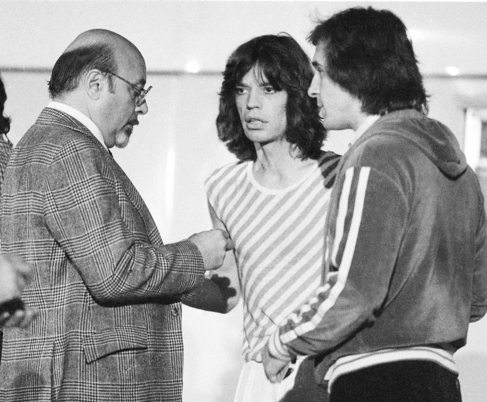 Ahmet Ertegun, head of Atlantic Records, talks to Mick Jagger and Peter Rudge, backstage at a Rolling Stones concert at Earls Court, London, May 1976. (Photo by Michael Putland/Getty Images)