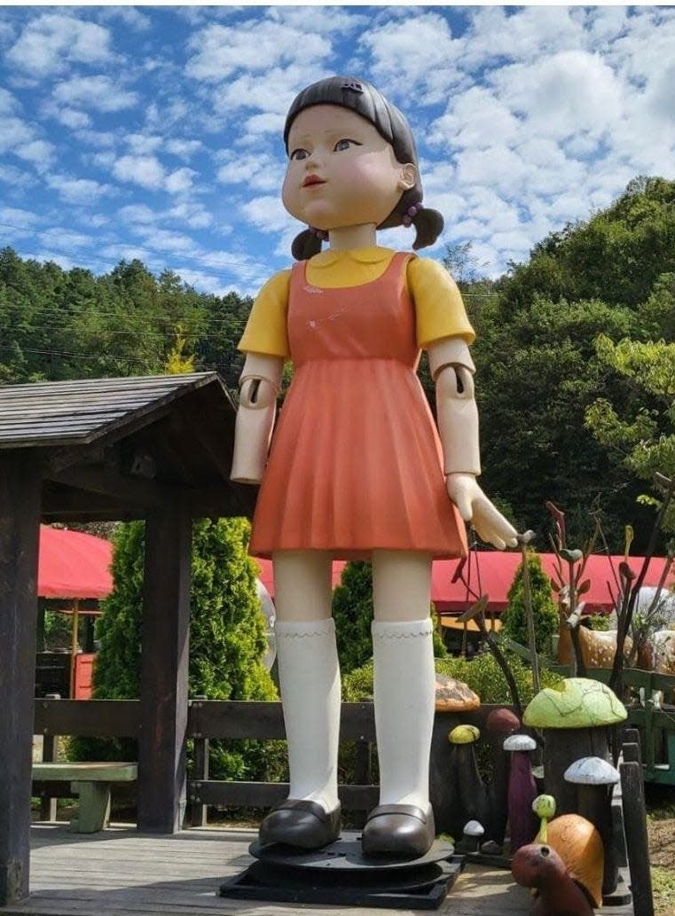 Doll from Squid Game standing at entrance of horse carriage museum