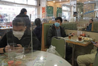 Customers have lunch with a transparent plastic panel setup on the table to isolate customers from spreading the coronavirus in Hong Kong, Wednesday, Feb. 12, 2020. China's ruling Communist Party needs to make a politically fraught decision: Admit a viral outbreak isn't under control and cancel this year's highest-profile official event. Or bring 3,000 legislators to Beijing next month and risk fueling public anger at the government's handling of the disease. (AP Photo/Kin Cheung)