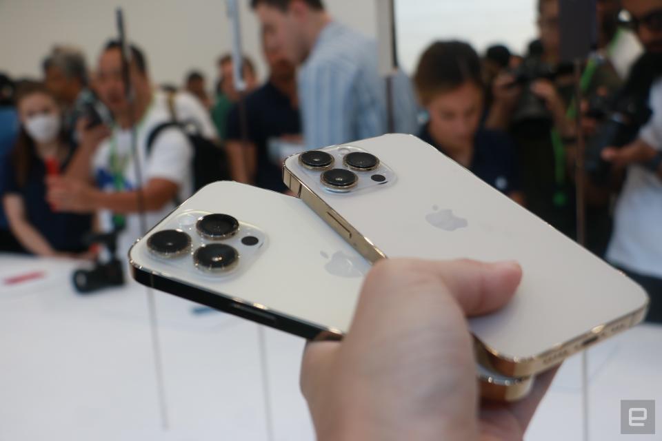 <p>Off-angle view of the iPhone 14 Pro and the iPhone 13 Pro held fanned out in one hand, with their rears facing the camera. The new model's cameras seem slightly bigger.</p> 