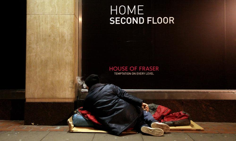 Homeless person in front of a shopfront sign reading 'Home second floor'.