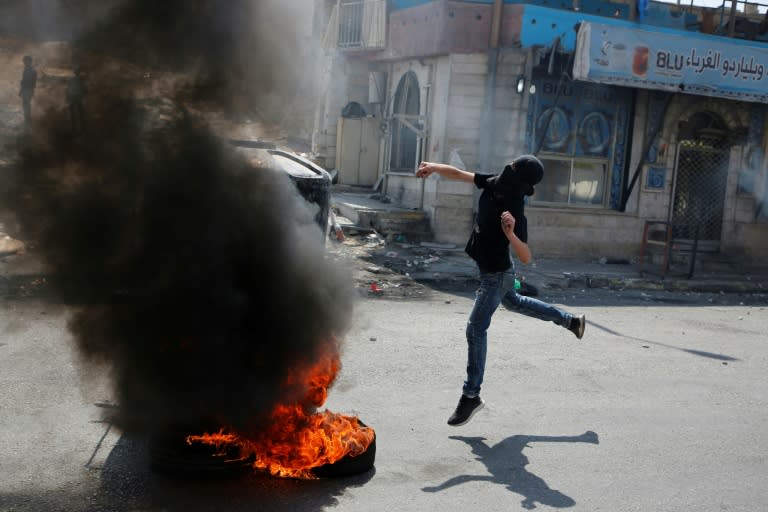 A masked Palestinian throws a stone towards Israeli troops during a protest on May 22, 2017 in support of the hunger strikers