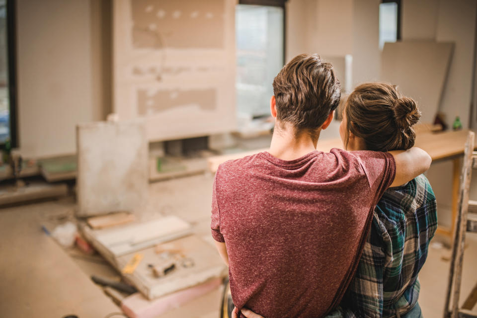 Rear view of loving couple standing embraced in their apartment that is renovating.